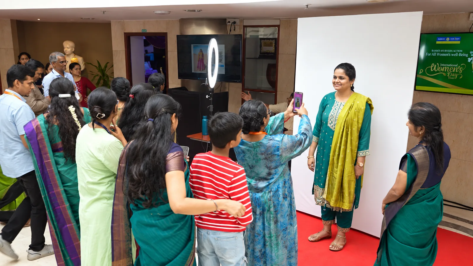 Guest posing at a Playtown AI Photobooth while colleagues take photos at a Women&rsquo;s Day event